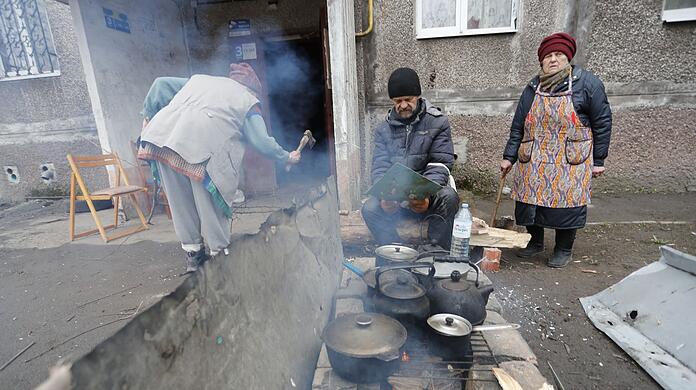 Einwohner kochen in Mariupol im Freien.