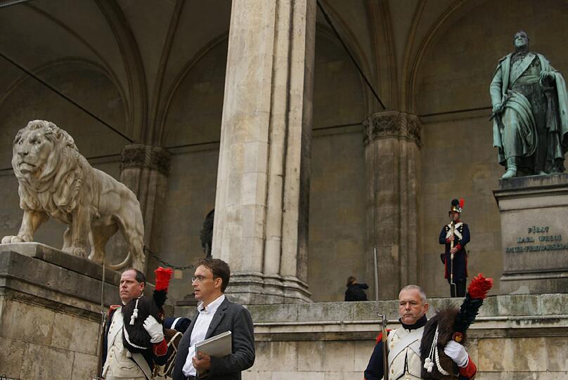 Die vielen Passanten und Touristen schauten verwundert auf dieses Szene: Drei Männer in historischen Soldatenuniformen standen am Freitag neben dem Denkmal des bayerischen Feldmarschalls Fürst Karl Wrede in der Feldherrnhalle am Odeonsplatz.
