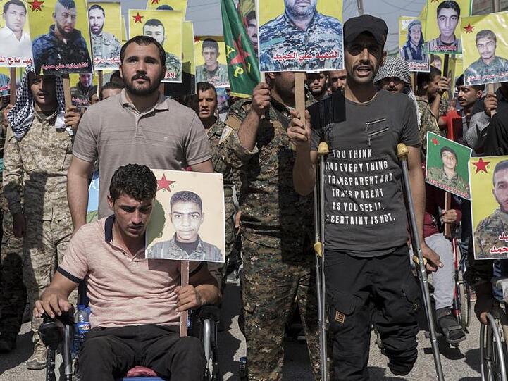 Verwundete kurdische Kämpfer präsentieren im nordostsyrischen Qamischli Bilder von Kameraden, die im Kampf gegen den IS getötet wurden.