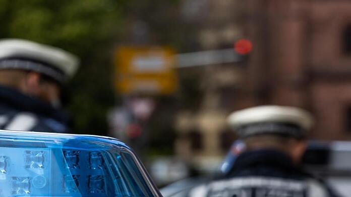 Zwei Polizeibeamte stehen zwischen Einsatzfahrzeugen.
