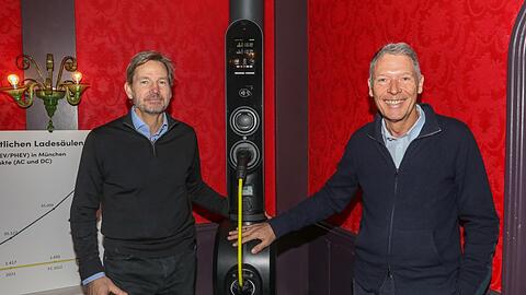 Henrik Thiele (l.) und Martin Kinne von Qwello zeigen bei einem Pressegespräch im Café Glockenspiel ihre Ladesäule. Das gelbe Kabel ist bis zu sechs Meter ausziehbar und wird am Ende wieder aufgerollt. "Hundert Prozent Ökostrom", versichert Thiele.