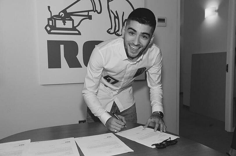 Zayn Malik strahlt über das ganze Gesicht, als er seinen ersten Solo-Plattenvertrag unterschreibt.