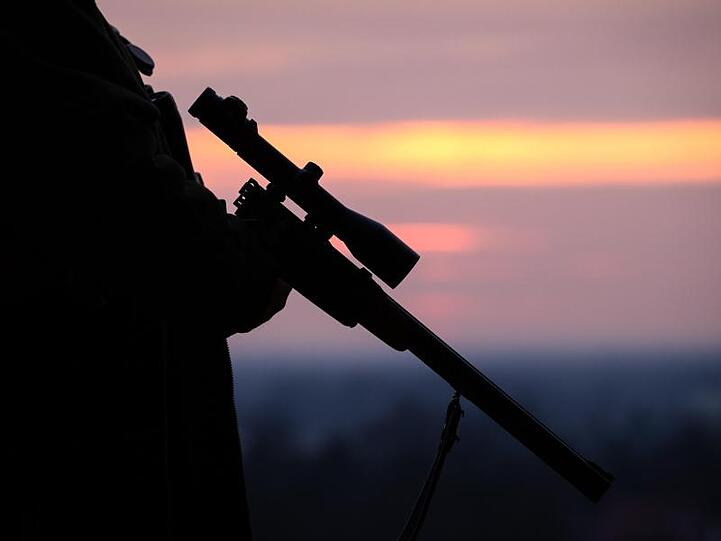 Ein Jäger hält sein Gewehr in der Abenddämmerung. Foto: Friso Gentsch/Archiv