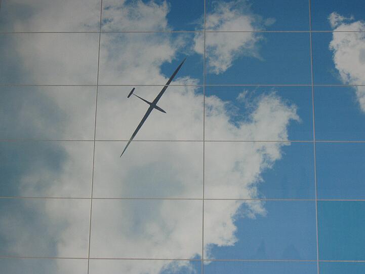 Ein Flugzeug nebst Wolken spiegelt sich im Tunnel.