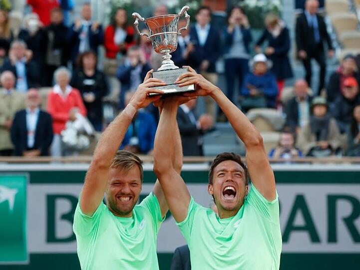 Kevin Krawietz (l) und Andreas Mies jubeln nach dem Turniersieg mit dem Pokal.