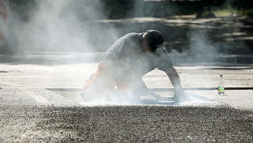 Ein Bauarbeiter repariert eine Stra&szlig;e in Berlin mit Bitumen, einem Bindemittel f&uuml;r Asphalt. (Symbolbild)
