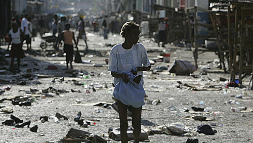 Der Hanger hat sich in Gewalt entladen. Eine Frau streift über einen zerstörten Markt in Haiti Der Hanger hat sich in Gewalt entladen. Eine Frau streift über einen zerstörten Markt in Haiti