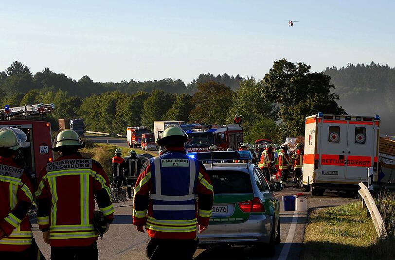 Feuerwehrleute stehen am Montag auf der Bundesstrasse 299 zwischen Aich und Egglkofen (Landkreis Mühldorf) nach einem Unfall mit einem Toten vor der Unfallstelle. Ein Autofahrer ist bei dem Verkehrsunfall ums Leben gekommen: Er hatte mit seinem Auto einen Lastwagen überholt und ist frontal mit einem entgegenkommenden Lkw zusammengestoßen, wie ein Polizeisprecher sagte.