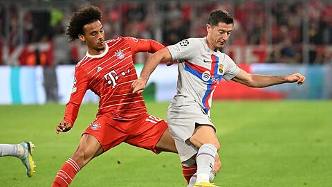 Bayerns Leroy Sané (l) versucht Barcelonas Robert Lewandowski vom Ball zu trennen.