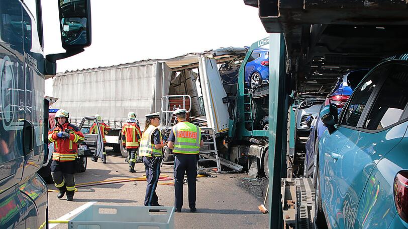 Polizisten und Feuerwehrleute stehen an der Unfallstelle auf der Autobahn 8. Bei der Karambolage wurde hier ein 35-Jähriger tödlich verletzt.