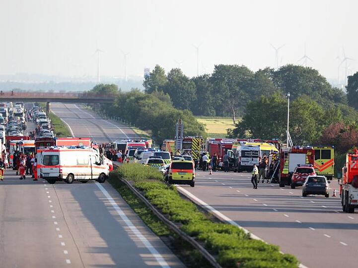 Einsatzkräfte der Feuerwehr und Rettungsdienst stehen an der Unfallstelle von einem verunglückten Bus. Foto: Jan Woitas