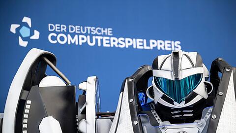 Der Gamescom Bot steht vor der Fotowand mit Schriftzug "Der Deutsche Computerspielpreis".