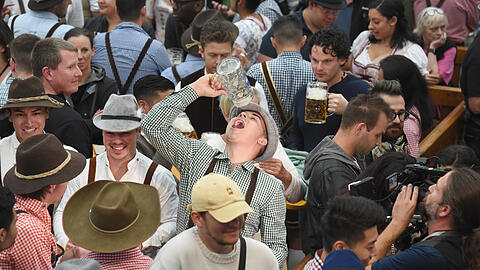 Der junge Mann macht es richtig – na ja, zumindest trinkt er nicht direkt aus dem Glas. Szene von der Wiesn 2022.