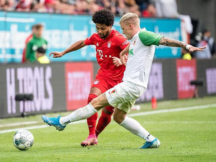 Bayerns Serge Gnabry (l) hat es gegen Augsburgs Philipp Max schwer.