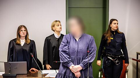 Die Angeklagte Andrea Tandler (2.v.r) steht zu Prozessbeginn an ihrem Platz im Gerichtssaal.