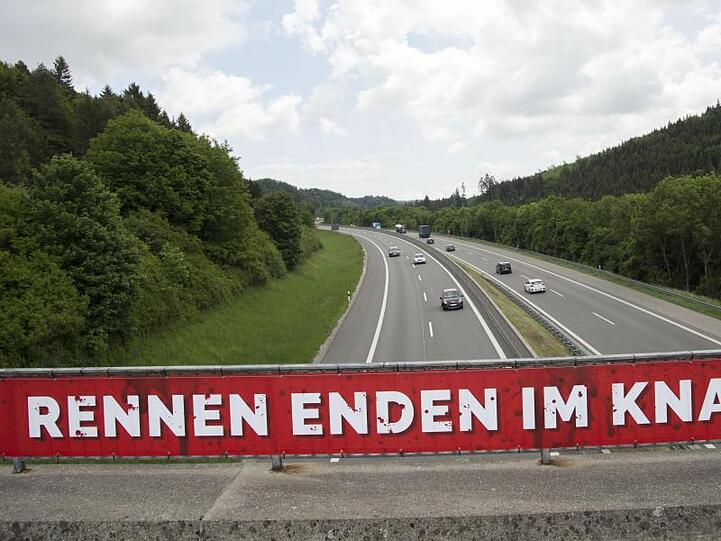 Ein Banner mit der Aufschrift "Rennen enden im Knast!" hängt an einer Autobahnbrücke. Foto: Steffen Schmidt/dpa/Symbolbild