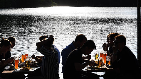Gäste sitzen in der Abendsonne im Seehaus-Biergarten am Kleinhesseloher See.