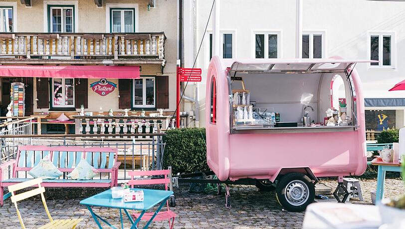 "Bevor Elisabeth Schwojer morgens die Türen zu ihrem Café öffnet, findet man sie häufig auf den umliegenden Bergen. Die Frische, die sie dort einfängt, bringt sie mit in ihr Elisabeths Platzerl. Dort backt, bastelt und wirbelt sie durch ihre rosa Welt. Ihr mobiles Café-Wagerl vor dem Haus ist unverkennbar und weithin sichtbar."