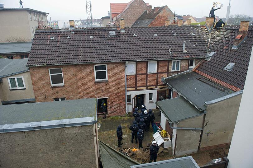 Die Besetzer werfen Konfetti, unten steht ein SEK-Kommando der Polizei: In Greifswald wurde ein besetztes Haus geräumt. Die Bilder.