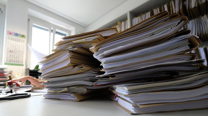 Akten liegen auf einem Tisch. Die Bürokratiebelastung in Deutschland hat in der Vergangenheit stetig zugenommen.