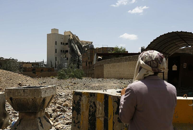 Eine Frau schaut auf die Zerstörung der Hauptstadt Sanaa