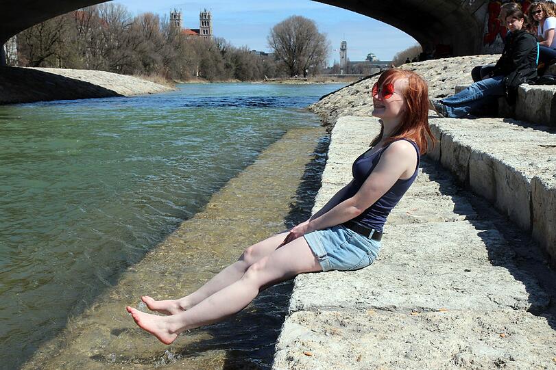 Anna aus Schweden genießt die warme Frühlingssonne an der kühlen Isar.