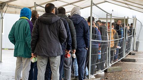 In der Landeserstaufnahmestelle im baden-württebergischen Ellwangen warten Flüchtlinge vor der Essensausgabe. Knapp 218.000 Menschen haben 2022 erstmals in Deutschland Asyl beantragt - so viele wie seit 2016 nicht.