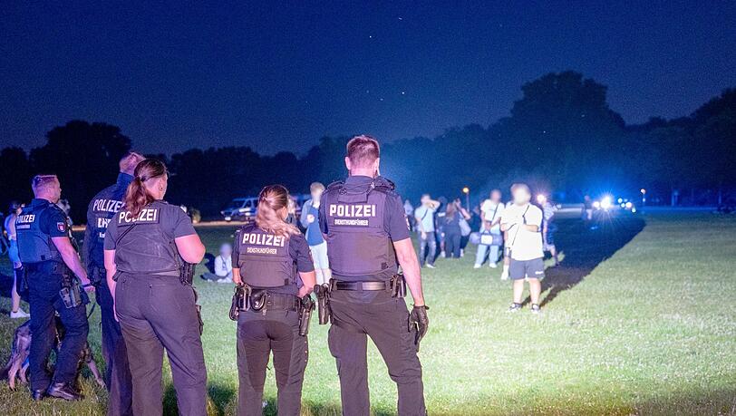 Einsatzkräfte der Polizei und Jugendliche stehen sich im Hamburger Stadtpark gegenüber.