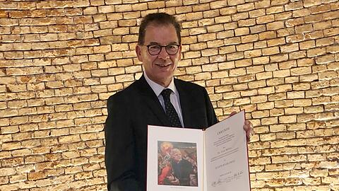Gerd Müller, ehemaliger Bundesentwicklungsminister, hält die Eugen-Biser-Preis-Auszeichnung in den Händen.