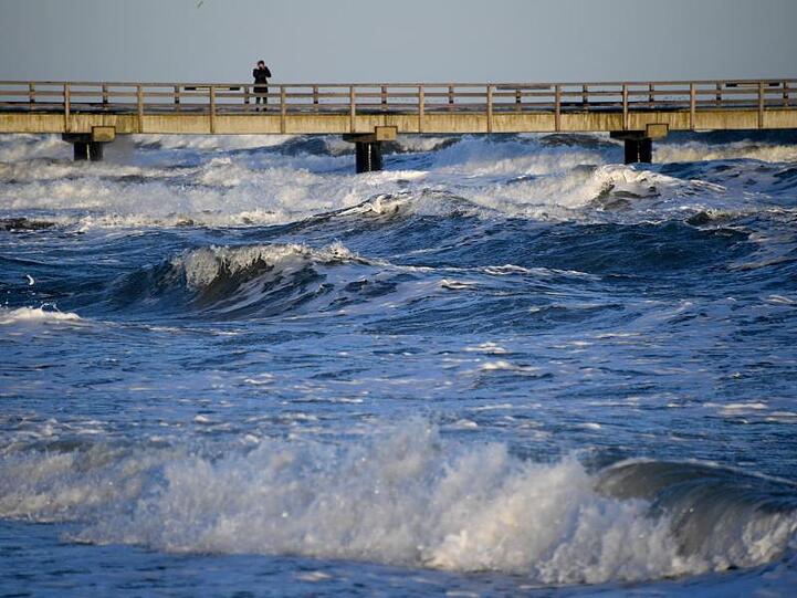 Wellen schlagen an die Seebrücke am Schönberger Strand. An der Ostseeküste wird eine Sturmflut mit einem Wasserstand von bis zu 1,50 Metern über Normal erwartet.