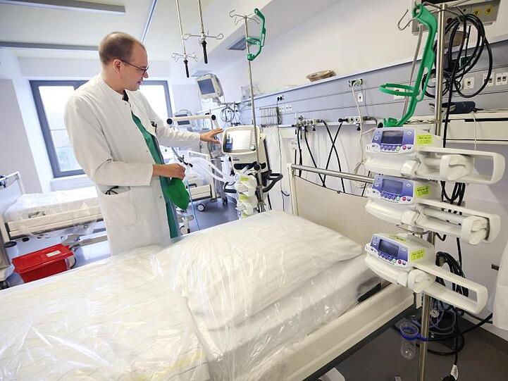 Ein Arzt steht neben einem Intensivbett im Krankenhaus. Foto: Roland Weihrauch/dpa/Symbolbild