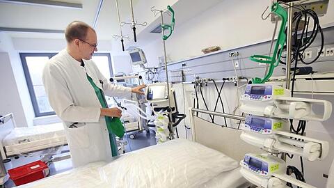 Ein Arzt steht neben einem Intensivbett im Krankenhaus. Foto: Roland Weihrauch/dpa/Symbolbild