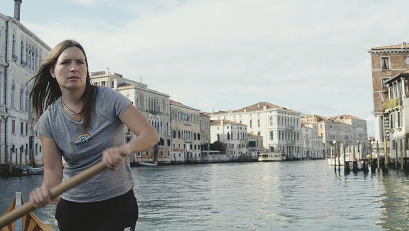 Eine Gondoliere, die sonst Ruderkurse für Touristen gibt, reflektiert über die ungewohnte Glätte des Wassers auf dem Canale Grande.