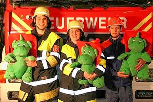 Junge Feuerwehrleute zeigen ihr Maskottchen Grisu.