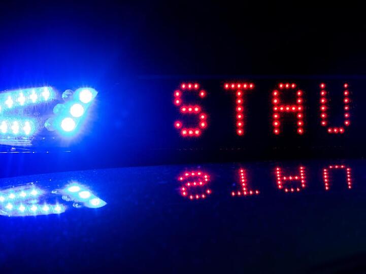 Das Blaulicht auf einem Polizeifahrzeug leuchtet, während sich das Display mit dem Wort "Stau" spiegelt. Foto: Monika Skolimowska/zb/dpa/Illustration