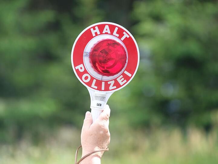 Eine Polizistin hält während einer Polizeikontrolle eine rote Winkerkelle in die Höhe. Foto: Sebastian Willnow/zb/dpa/Archivbild