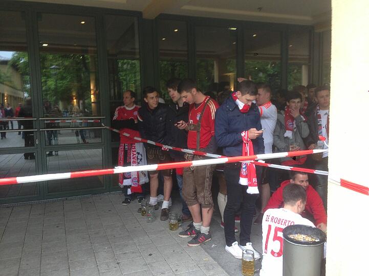 Die ersten Fans warten bereits seit 12 Uhr. Geöffnet wird der Innenraum aber erst um 19 Uhr! Dafür Lederhosen, Trikots und Fahnen en masse. BVB-Fans sind hier kaum zu sehen.