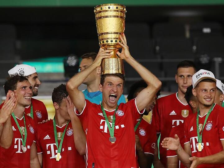 Münchens Thomas Müller hält die Trophäe nach dem Spiel hoch.
