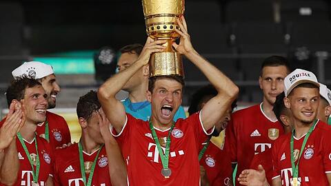 Münchens Thomas Müller hält die Trophäe nach dem Spiel hoch.