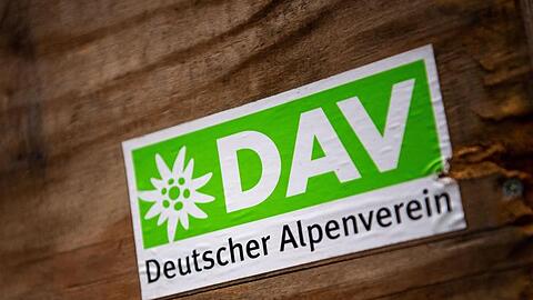 Das Logo des Deutschen Alpenverein (DAV) klebt auf einer Holzbox. Foto: Lino Mirgeler/dpa