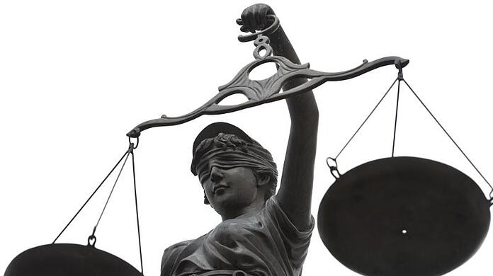 Eine Statue der Justitia mit einer Waage in ihrer Hand.