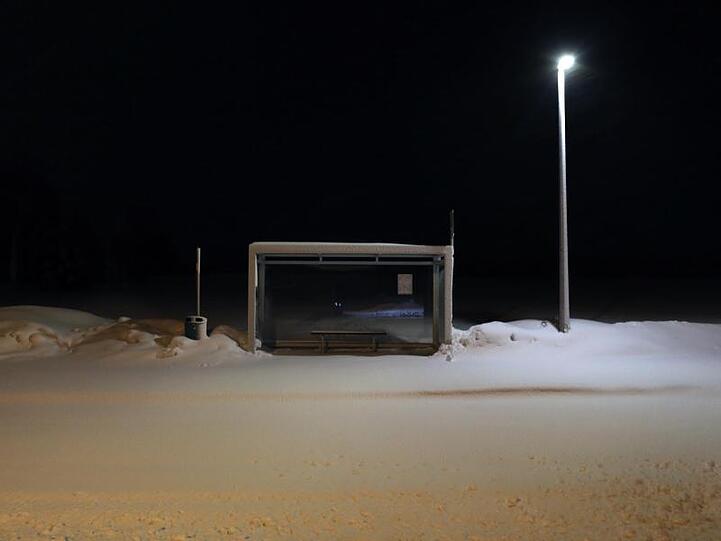 Eine Bushaltestelle an einer mit Neuschnee bedeckten Straße in Ruderatshofen.