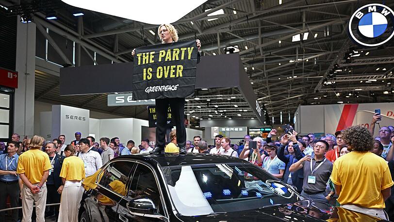 Eine Greenpeace-Aktivistin steht bei der Eröffnung der IAA auf dem Dach eines ausgestellten Autos.