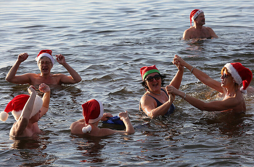 Beim traditionellen Weihnachtsbaden amüsieren sich "Pirrliepausen" (norddeutsch: Eiszapfen) am 24.12.2015 in Senftenberg (Brandenburg) im sechs Grad kalten Senftenberger See.