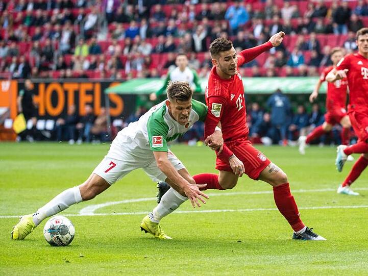Augsburgs Florian Niederlechner (l) und Bayerns Lucas Hernandez liefern sich einen harten Schlagabtausch.
