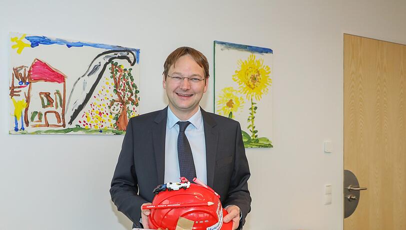 Bau- und Verkehrsminister Hans Reichhart in seinem Büro. Den Bauhelm hat er von seinem Onkel, die Bilder haben seine Kinder gemalt.
