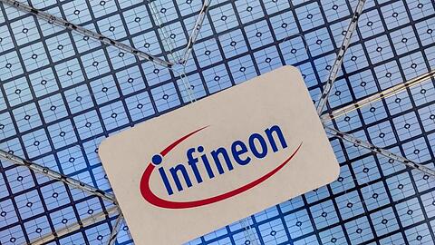 Das Infineon-Logo klebt auf einem Wafer im Showroom des Unternehmens. Foto: Peter Kneffel/dpa/Archivbild