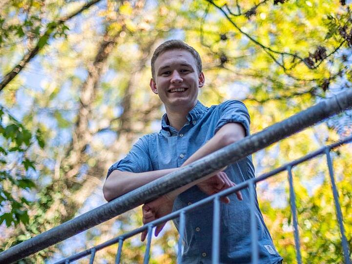 Florian Siekmann (Grüne), Jüngster Abgeordneter des bayerischen Landtags, lehnt an einem Zaun. Foto: Lino Mirgeler/Archiv