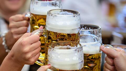 Besucher stoßen auf dem Oktoberfest mit Bier an.
