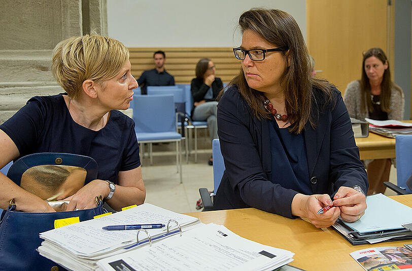 Susanne Herrmann (r.), Stadtdirektorin der Stadt München, und Claudia Janke, Leiterin der Kita-Elternberatung, unterhalten sich in einem Sitzungssaal im Verwaltungsgerichtshof in Ansbach vor Prozessbeginn.